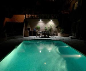 una piscina por la noche con una mesa en el fondo en Rez-de Villa Piscine, en Cavalaire-sur-Mer