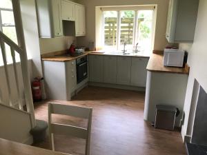 a kitchen with white cabinets and a sink and a table at North Lodge in Invergarry