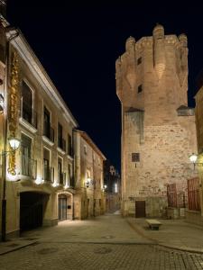 un vieux bâtiment avec un château la nuit dans l'établissement Luxor Torre del Clavero Apartments, à Salamanque