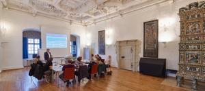 a group of people sitting at tables in a room with a presentation at Schloss Weinberg in Kefermarkt
