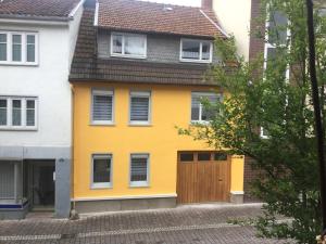 a yellow house with a wooden door on a street at deinFerienhaus Scheliga „Midi“ in Bad Sobernheim