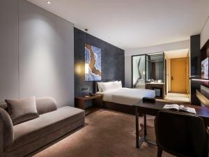 深圳Mercure Shenzhen Longgang的配有床和书桌的酒店房间