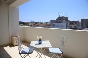 a table and chairs on a balcony with a vase of flowers at Arcadia penthouse appartment Otranto in Otranto