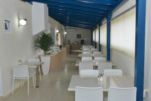 uma fila de mesas e cadeiras brancas num restaurante em Hotel Venus em Fourka