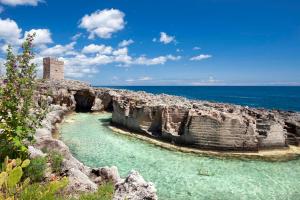 Blick auf eine Felsklippe mit Wasser und ein Schloss in der Unterkunft Casa di Rosaria - Due appartamenti nel centro storico con giardino sul terrazzo in Depressa