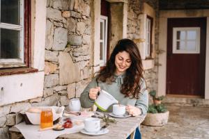 a woman sitting at a table with a cup of coffee at Casas de Pedra - Quinta da Escola in Alvados