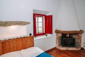 a bedroom with a fireplace and a red window at Casas de Pedra - Quinta da Escola in Alvados