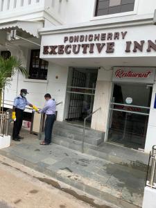 Dwóch mężczyzn stoi przed budynkiem. w obiekcie Pondicherry Executive Inn w mieście Puducherry