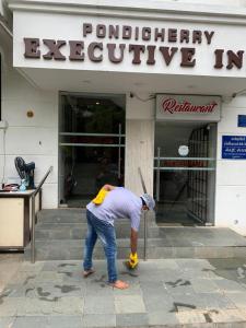 un hombre está parado frente a un edificio en Pondicherry Executive Inn en Pondicherry
