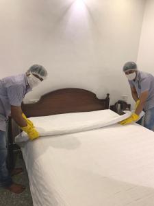 two people are working on a bed in a room at Pondicherry Executive Inn in Pondicherry