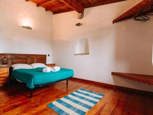 a bedroom with a green bed and a wooden floor at Casas de Pedra - Quinta da Escola in Alvados