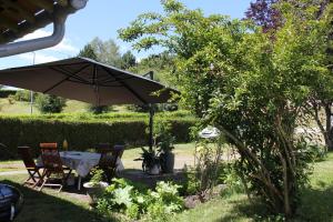 uma mesa e cadeiras sob um guarda-sol num jardim em FLAMBOYANT em Bussang