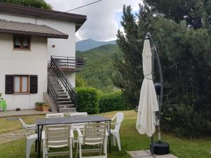 a table with a white umbrella and chairs and a house at Appartamenti Bice Abetone in Abetone