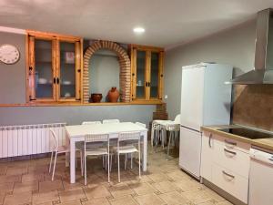 a kitchen with a table and a white refrigerator at Casa MARIA VILLARROYA in Villarroya