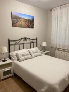 una camera da letto con un grande letto bianco con due comodini di Casa MARIA VILLARROYA a Villarroya