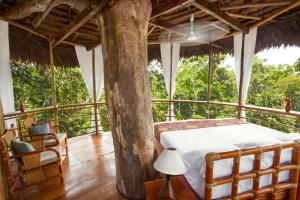 a bedroom in a tree house with a bed and chairs at Treehouse Lodge in Yucuruche