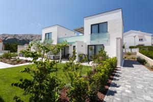 una casa blanca con un patio verde en Hotel & Resort ISOLA, en Baška