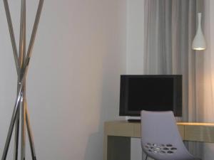 a white chair sitting in front of a desk with a television at Funchal Design Hotel in Funchal