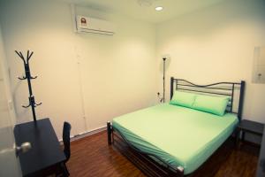 een kleine slaapkamer met een bed en een bureau bij The Haven Inn in Melaka