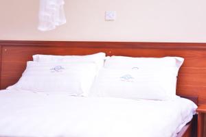 a bed with white sheets and pillows on it at Nabisere Hotel Kalisizo in Kalisizo