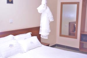 a white robe hanging on a wall above a bed at Nabisere Hotel Kalisizo in Kalisizo
