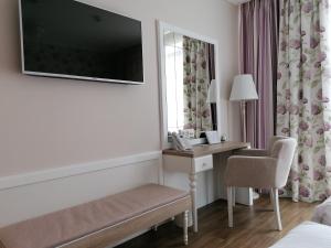 a hotel room with a desk and a television on the wall at Impresamente Art Hotel in Sofia