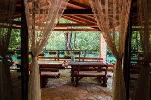 a table and benches in a pavilion with curtains at Vacation Home Hercegovka in Čapljina