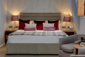 Corus Hyde Park Hotel في لندن: غرفة نوم بسرير كبير ومخدات حمراء وبيضاء