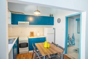 cocina con armarios azules y mesa de madera en Cozy House with Flowery Courtyard in Notable Location, en Rodas