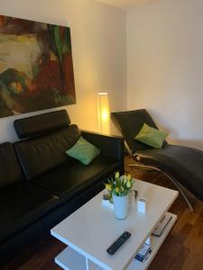 Sala de estar con sofá negro y mesa de centro en Fewo Domizil am Dom, en Trier