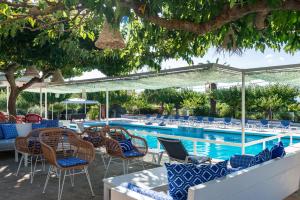 einen Pool mit Stühlen, einem Tisch und einem Pool in der Unterkunft Sirocco Hotel in Zakynthos