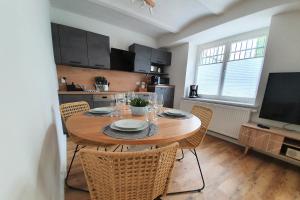 a kitchen with a wooden table with chairs and a television at PB Ferienwohnungen - FeWo 1 - Stilvoll eingerichtetes Apartment im Herzen Senftenbergs in Senftenberg +5 photos