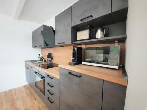 eine Küche mit Spüle und Mikrowelle in der Unterkunft PB Ferienwohnungen - FeWo 1 - Stilvoll eingerichtetes Apartment im Herzen Senftenbergs in Senftenberg