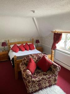ein Schlafzimmer mit einem Bett und einem Sofa mit roten Kissen in der Unterkunft Greyhound Country Inn in Honiton