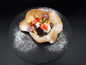 een zwarte plaat met een dessert met fruit erop bij Locanda Da Piero in Mirano