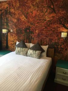 a bedroom with a white bed with a tree mural at The White Horse Inn in Cambridge