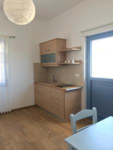 une cuisine avec des placards en bois, une table et une fenêtre dans l'établissement Vegera Apartment 'Sofrano', Stavros Donoussa, à Donoussa