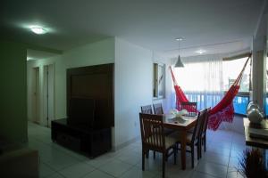 ein Wohnzimmer mit Tisch und Stühlen und einem Fernseher in der Unterkunft Suíte Guarapari - 3 quartos na Praia das Virtudes in Guarapari + 9 Fotos