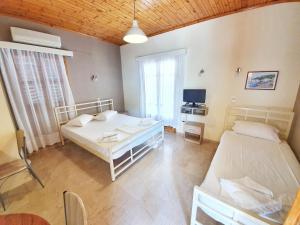 Habitación con 2 camas, mesa y TV. en Alexaria Holidays Apartments, en Lefkada