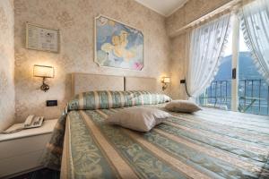 a bedroom with a bed with a phone and a window at Hotel Miralago in Cernobbio