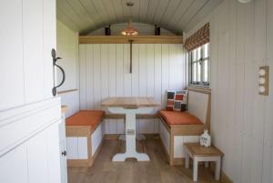 a small room with a table and benches in a house at Perkins luxury shepherd huts in Nottingham