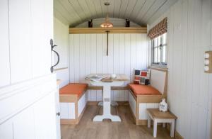 een kleine kamer met een tafel en banken. bij Perkins luxury shepherd huts in Nottingham