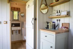 een kleine keuken met witte kasten en een spoelbak bij Perkins luxury shepherd huts in Nottingham +4 foto's