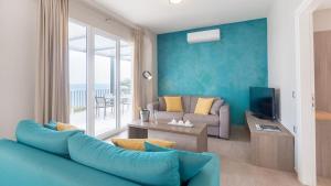 a living room with a couch and a tv at Blue Jasmine Hotel in Skala Kefalonias