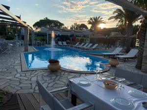 a swimming pool with a table and chairs and a table at Vergos Hotel in Vourvourou