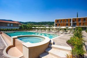 una piscina con sillas y sombrillas y un edificio en Residenza Olivo, en Garda