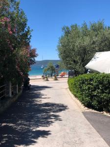 um passeio que leva a uma praia com árvores e o oceano em Apartments Perla em Biograd na Moru