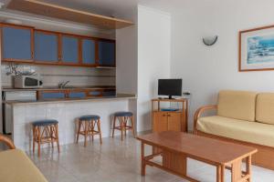 - un salon avec un canapé, une table et des chaises dans l'établissement Aparthotel Calema Avenida Jardim, à Monte Gordo