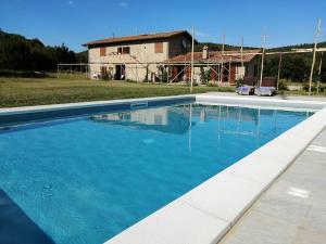 a swimming pool with blue water in front of a house at Casa Campione in Roccastrada