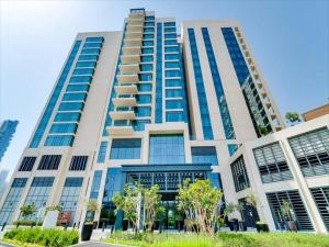 a tall building with blue windows and trees at Lux BnB Vida Residences The Hills-3BDR+Maids Golf Course View in Dubai